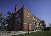 Thumbnail 100 of 100 - A large brick building with a brown door and windows.