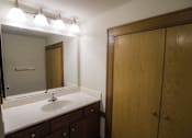 Thumbnail 11 of 100 - A bathroom with a sink, mirror, and wooden cabinet.