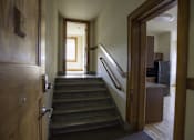 Thumbnail 16 of 100 - A hallway with a staircase and a door on the left.