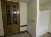 Thumbnail 20 of 100 - A bathroom with a wooden door and a white bathtub.