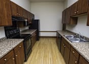 Thumbnail 25 of 100 - A kitchen with wooden cabinets and black appliances.
