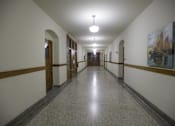Thumbnail 44 of 100 - A long hallway with a light on the ceiling and a painting on the wall.
