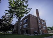 Thumbnail 49 of 100 - A large brick building with a tree in front of it.