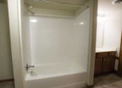 Thumbnail 62 of 100 - A white bathtub with a silver faucet is in a bathroom.
