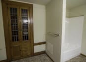 Thumbnail 70 of 100 - A bathroom with a wooden door and a white bathtub.