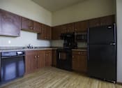 Thumbnail 7 of 100 - A kitchen with black appliances and wooden cabinets.