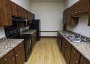 Thumbnail 75 of 100 - A kitchen with wooden cabinets and black appliances.