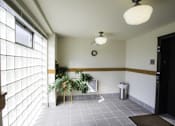Thumbnail 79 of 100 - A hallway with a tiled floor, a trash can, and a plant.