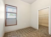 Thumbnail 9 of 29 - A room with a carpeted floor, a window, and an open door.