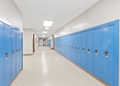 Thumbnail 5 of 29 - A long hallway with blue lockers on both sides.