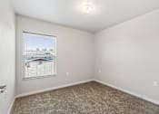 Thumbnail 24 of 29 - A room with a carpeted floor and a window showing a view of a house.