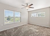 Thumbnail 19 of 29 - A room with a ceiling fan and two windows.
