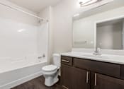 Thumbnail 29 of 29 - A white toilet sits in a bathroom with brown cabinets.