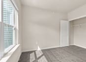 Thumbnail 4 of 16 - A room with a carpeted floor, a white door, and a window with blinds.
