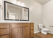 Thumbnail 5 of 16 - A bathroom with a wooden vanity and a white toilet.