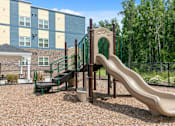 Thumbnail 11 of 16 - A playground with a slide and a green fence.