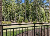 Thumbnail 15 of 16 - A green fence in front of a forest.