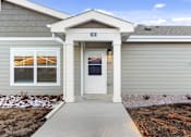 Thumbnail 10 of 32 - A house with a grey siding and a white door is numbered 10.