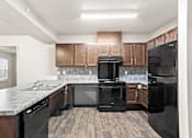 Thumbnail 12 of 32 - A kitchen with black appliances and wooden cabinets.