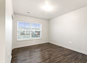 Thumbnail 16 of 32 - Empty room with a window and wooden flooring.