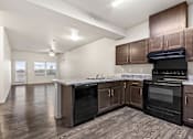 Thumbnail 26 of 32 - A kitchen with dark wood cabinets and black appliances.
