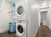 Thumbnail 27 of 32 - A white washing machine and dryer in a small laundry room.