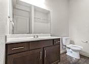 Thumbnail 28 of 32 - A white toilet sits next to a sink in a bathroom.