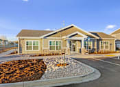 Thumbnail 6 of 32 - A building with a brown roof and a grey stone border in front.