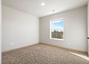 Thumbnail 5 of 27 - A room with a carpeted floor and a window showing a view of trees and sky.