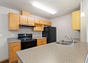 Thumbnail 24 of 27 - A kitchen with a black refrigerator, stove, and oven.