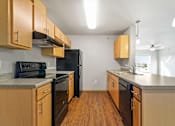 Thumbnail 19 of 27 - A kitchen with wooden cabinets and black appliances.