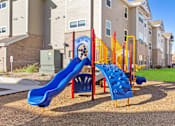 Thumbnail 18 of 27 - A playground with a blue slide and a red and yellow climbing structure.
