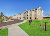 Thumbnail 20 of 27 - Apartment complex with a green lawn and a walkway.