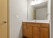 Thumbnail 27 of 27 - A bathroom with a wooden door and a mirror above a sink.
