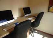 Thumbnail 7 of 18 - A black chair is in front of a desk with two monitors and a keyboard.