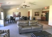 Thumbnail 9 of 18 - A living room with a grey couch and a ceiling fan.