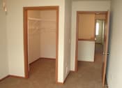 Thumbnail 15 of 18 - A room with a brown carpet and a white wall with a doorway leading to another room.