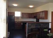 Thumbnail 12 of 15 - A kitchen with wooden cabinets and a black refrigerator.