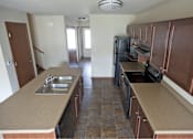 Thumbnail 3 of 15 - A kitchen with brown cabinets and a black refrigerator.