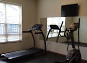 Thumbnail 15 of 15 - A home gym with a treadmill, a stationary bike, and a chair.