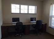 Thumbnail 4 of 15 - Two computers are on a desk in a room with two windows.