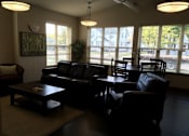 Thumbnail 6 of 15 - A living room with a black leather couch and a coffee table.