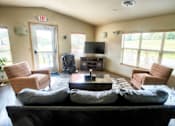 Thumbnail 2 of 25 - A living room with a couch, chairs, and a television.