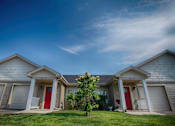 Thumbnail 6 of 25 - Two houses with red doors and garages are shown with a tree in between.