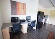 Thumbnail 11 of 25 - A room with a desk, chairs, and a fridge.