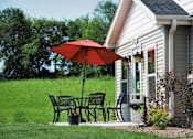 Thumbnail 1 of 25 - A red umbrella is on a patio table outside a house.