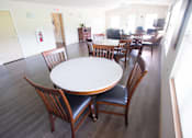 Thumbnail 9 of 25 - A round table with chairs around it in a room.