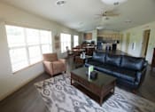 Thumbnail 8 of 25 - A living room with a black leather couch and a coffee table.