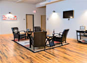 Thumbnail 22 of 33 - A conference room with a wooden floor and a white wall with a TV.