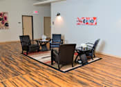 Thumbnail 21 of 33 - A conference room with a wooden floor and a white wall with a red and white poster.